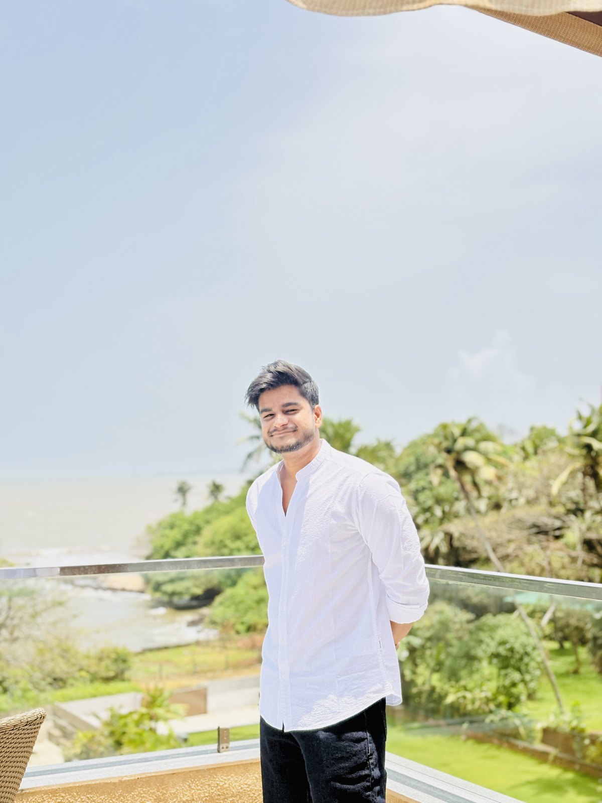 Sanskar Shivhare in a white shirt on a balcony overlooking the coast